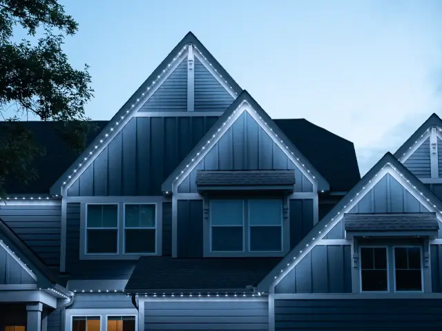 Warm-white permanent roofline lighting on a home at night